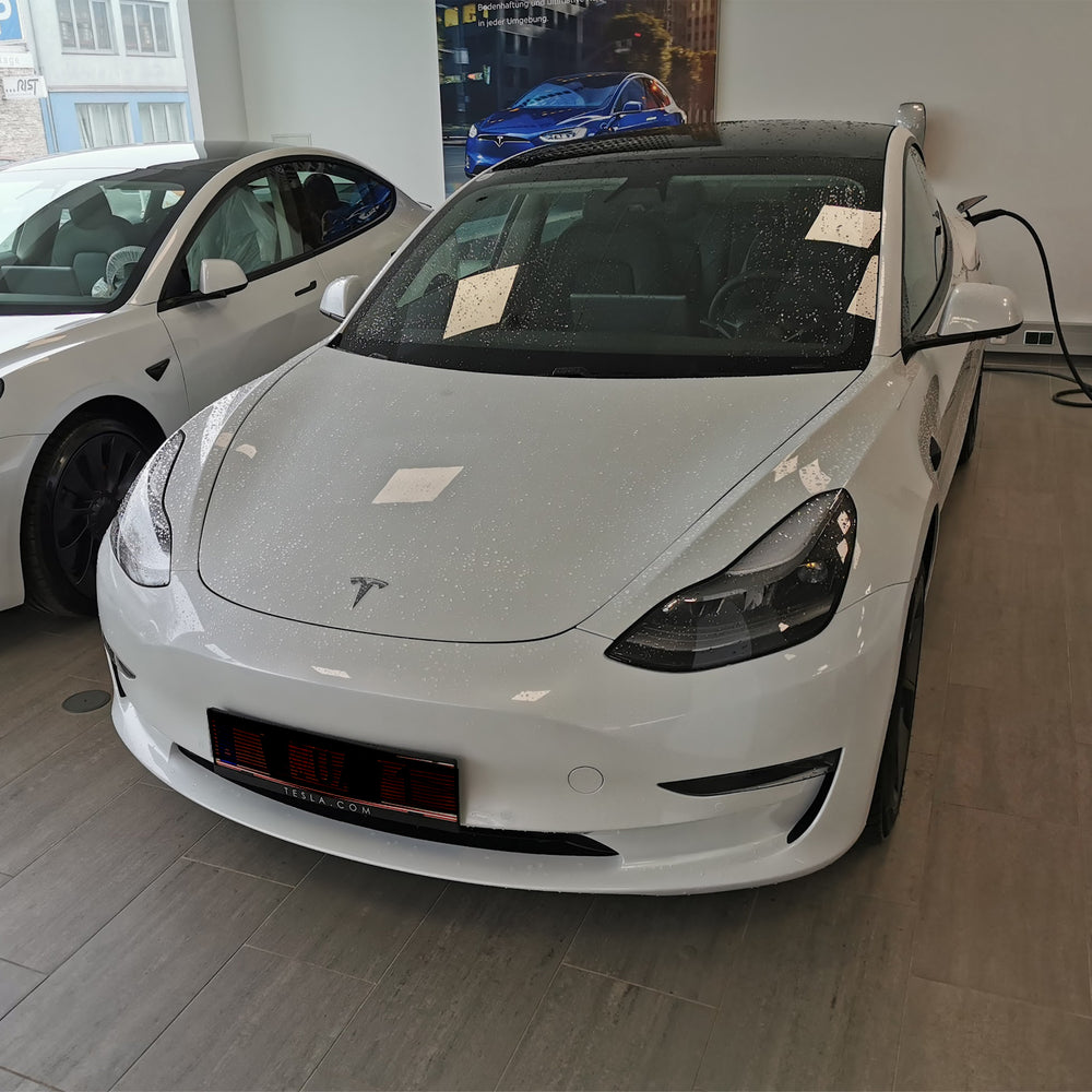 Weißes Tesla Model 3 bei der Übergabe im Showroom