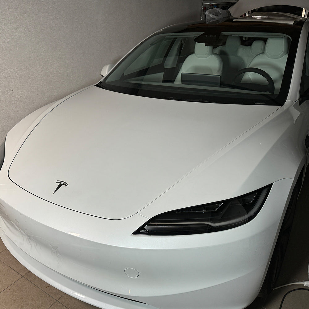 Weißes Tesla Model 3 „Highland“ von vorne in der Werkstatt
